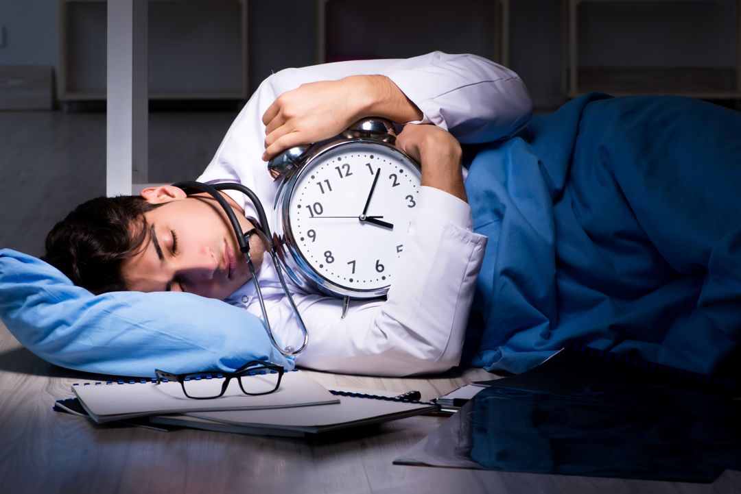 Doctor sleeping on the floor with a clock in his hands